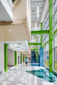 Young student walking down a dappled, daylit corridor at Bethel-Hanberry School. 